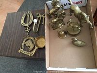 Overall lot showing all brass items including carousel horse, unicorn figure, smaller horses, bell, key holder, horseshoe knocker, and paperweight.
