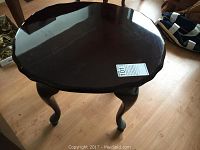 Photo of the round solid wood side table top with a scalloped edge and high gloss dark finish