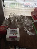 Glass punch bowl with matching stemmed glasses arranged around it, showing intricate cut starburst patterns.