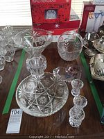 Wide shot showing multiple Mikasa crystal dishes and bowls with star and floral cut patterns on a table, along with boxed items in the background.
