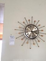Phinney Walker sunburst wall clock mounted on wall with descriptive lot tag.