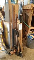 Several axes and sledge hammers grouped together showing wooden handles and metal heads with wear and rust, storage area background.