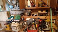 Cluttered workbench area with jars, tins, boxes, hand tools, and hardware items