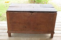 Front view of the antique primitive wooden chest showing the aged wooden surface and legs.