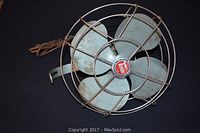 Front top view showing fan blades, center Toucan emblem, and wire protective cage.