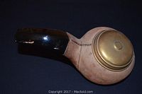 Full view of the pipe-shaped cigarette dispenser showing suede body and glossy black mouthpiece with brass lid.