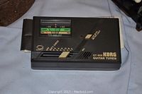 Close-up image of the Korg GT-60X guitar tuner showing the analog meter and controls