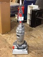 Front view of the Dyson DC14 upright vacuum cleaner showing its full height, handle, hose attachment, and dust bin.
