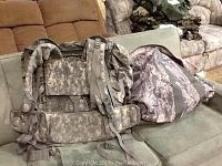 Two bags displayed on a couch, one military style backpack and one duffel bag both in camouflage patterns, showing their overall condition and details