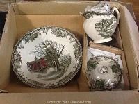 Photo of a ceramic serving bowl and matching cream and sugar bowl with lid inside a cardboard box, showing green landscape and barn designs.