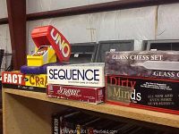 Photo of multiple boxed games lined up, showing Fact or Crap, Sequence, Scrabble, Uno card holders, Glass chess set, and Dirty Minds.