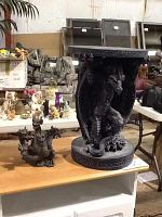 Photo showing a small dragon table with a detailed dragon base and a separate multi-headed dragon figurine on a wooden surface, surrounded by other various collectibles in the background.