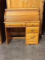 Front view of wooden roll top desk showing drawers, roll top cover, and design details.
