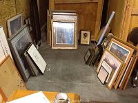 Multiple framed prints grouped on concrete floor