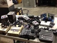 Overhead view of all consoles, controllers, game cartridges, discs and cables on table