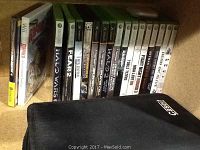 Xbox and Xbox 360 games lined up along the back wall with a black Qasey carrying case in front.