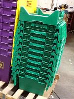 Stack of ten green plastic storage crates on pallet