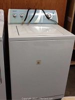 White Admiral top-loading washing machine with water hoses attached and control panel with knobs visible.