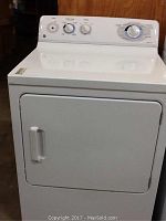 Front view of a white GE electric dryer showing front door, handle, and three control knobs with one knob missing on the left side.