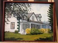 Overall front view of painting showing a white two-story house with porch, bushes, and trees painted on board in a wooden frame.
