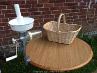 Full view of manual tomato seed separator mounted on a round wooden table next to the wicker basket.
