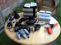 Two NES consoles stacked, SNES console, assorted controllers and light guns on table