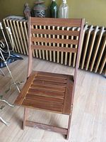 Full front view of the wooden folding chair showing back slats and seat.