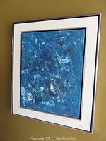 Framed abstract acrylic painting on canvas hung on wall, showing full artwork with blue dominant colors.