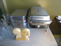 Full view of stainless steel chafing dish, roasting pan, and horse head stone bookends on table