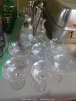 Photo showing 10 clear crystal wine glasses with floral etching on a table, arranged in two rows.