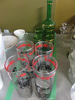 Green glass decanter with six matching green glasses and four vintage highball glasses with red and black horse and carriage design.