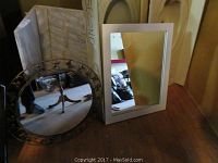 Two framed mirrors side by side; oval mirror with decorative metal frame and rectangular mirror with white frame, showing condition and style.