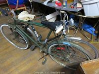 Side view of vintage CCM green bicycle with two seats and rust damage.