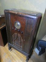 Full view of the vintage wooden console radio, showing overall tall cabinet and carved details.