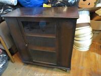 Closed cabinet showing dark wood finish and glass door.