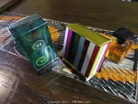 Photo of all three perfume items including the boxed Smart Collection No. 07, the Coach Eau De Parfum boxed in multicolor stripes, and a small amber liquid perfume bottle labeled Madly Eau De Toilette with black cap.