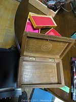 Open view of a carved wood box showing plain interior, visible screw sticking out and scratches on wood surface.