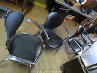Set of four black resin and metal Allseating chairs shown together from above angle, highlighting overall set and condition.