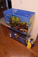 Photo showing Aqua-Tech aquarium box sitting on top of the glass aquarium along with a yellow and blue bag with aquarium supplies.