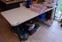 White folding table with items on top and underneath. Shows overall size and context of table.
