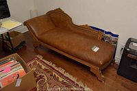 Full side view of the lounge chair showing leather upholstery and carved wooden legs and frame.