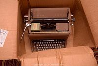 Top view showing the Underwood typewriter inside a cardboard box with some accessories on top.