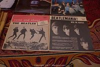 Photo showing four LP vinyl record covers laid out on a patterned carpet. Includes 'Twist and Shout' and 'Beatlemania' by The Beatles, and E.T. soundtrack covers.