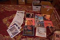 Photo shows collection of LP records arranged on a patterned rug with some in boxes nearby. Album covers and sleeves are visible including classical music titles and popular artists.