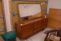Full view of wood dresser with attached rectangular mirror and nine drawers.