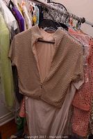 Beaded pearl-embellished crop top layered over nude gown hung on rack