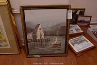 Frontal view of oil painting in ornate frame showing dock, boathouse, and sailboat scene.