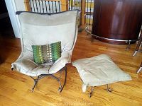 Beige cushioned rocking chair with green decorative pillow, and matching cushioned foot rest next to it on wooden floor.
