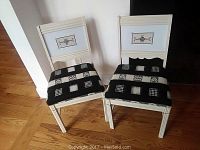 Two matching white wooden accent chairs with black and white patterned seat cushions, shown side by side on hardwood flooring.