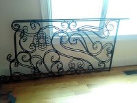 Ornate black metal bed frame with scrollwork design.